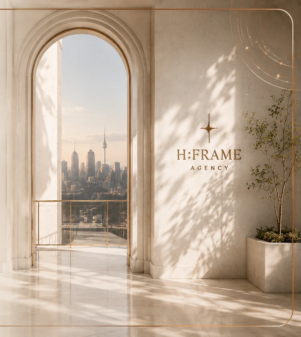 Sunlit pearl-ivory H:FRAME architectural interior with a copper-trimmed arch, city view and H:FRAME Agency wall mark.