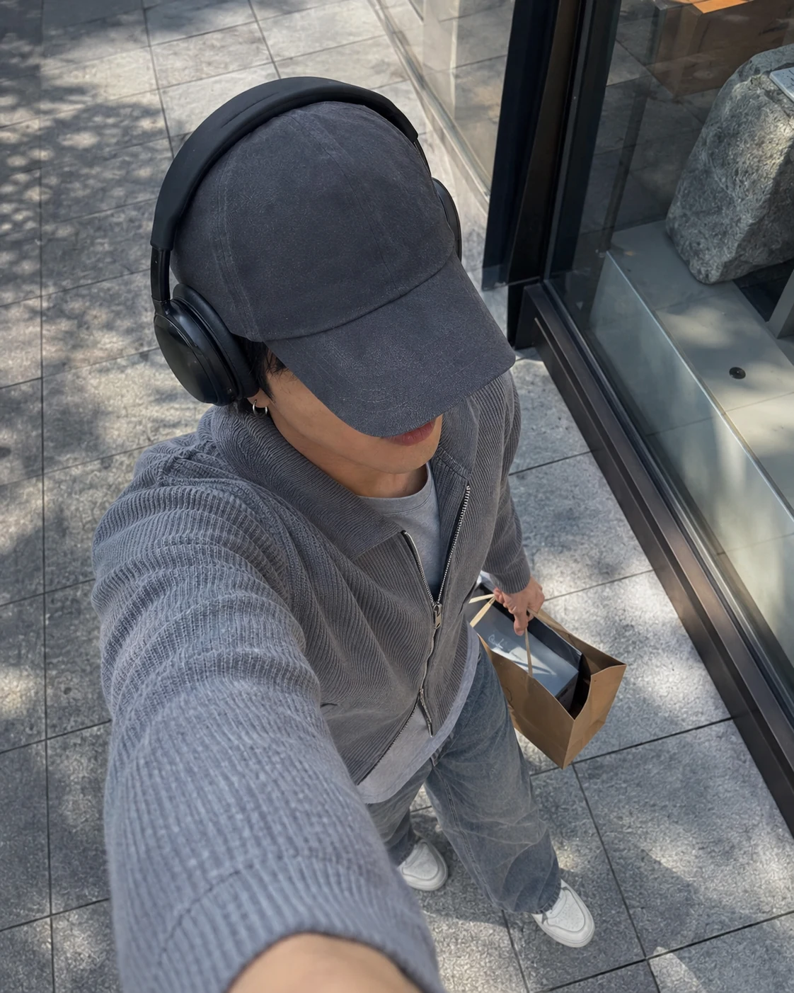 Faceless overhead lifestyle photograph of Lee Joon-Seok in a grey cap and headphones.
